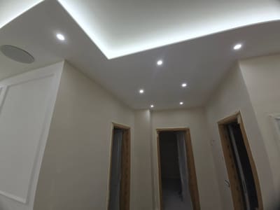 Disimpegno con tre porte, controsoffitto con luce LED nascosta lungo il bordo e faretti incassati.
