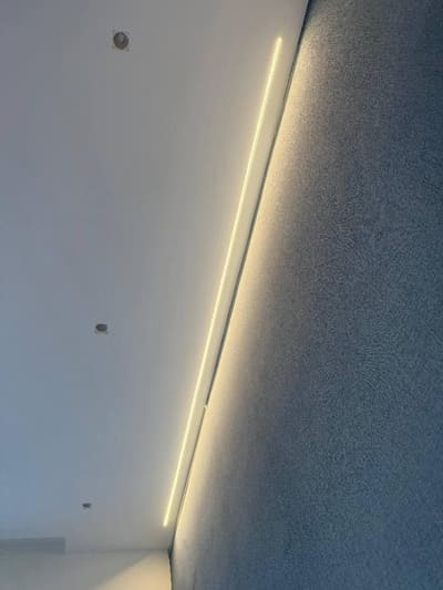 Linea di luce calda che corre lungo l'angolo tra il soffitto bianco e una parete blu.